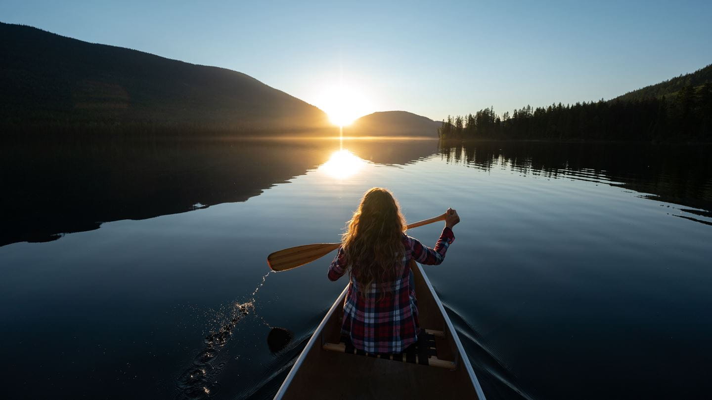 Woman canoeing on a stunning mountain lake