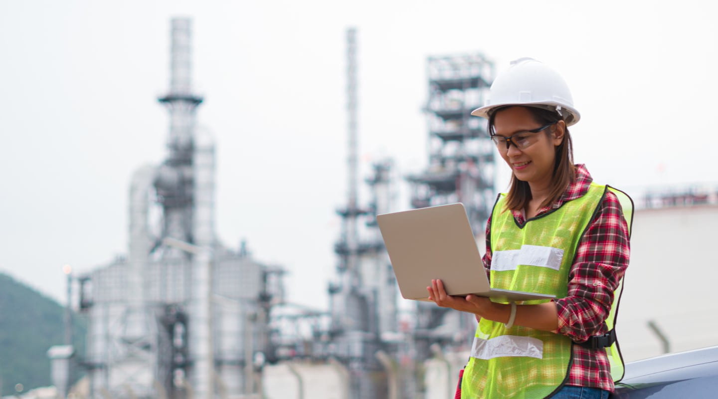Engineer reading email on laptop outside plant