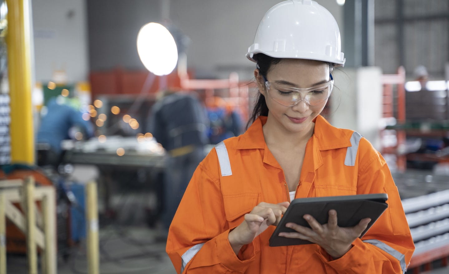 Female engineer in protective equipment looking at tablet