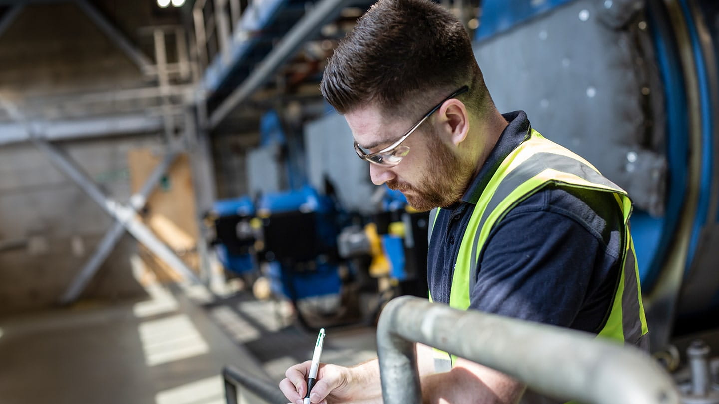 Service Ingenieur macht sich Notizen bei einer Anlagenbegehung